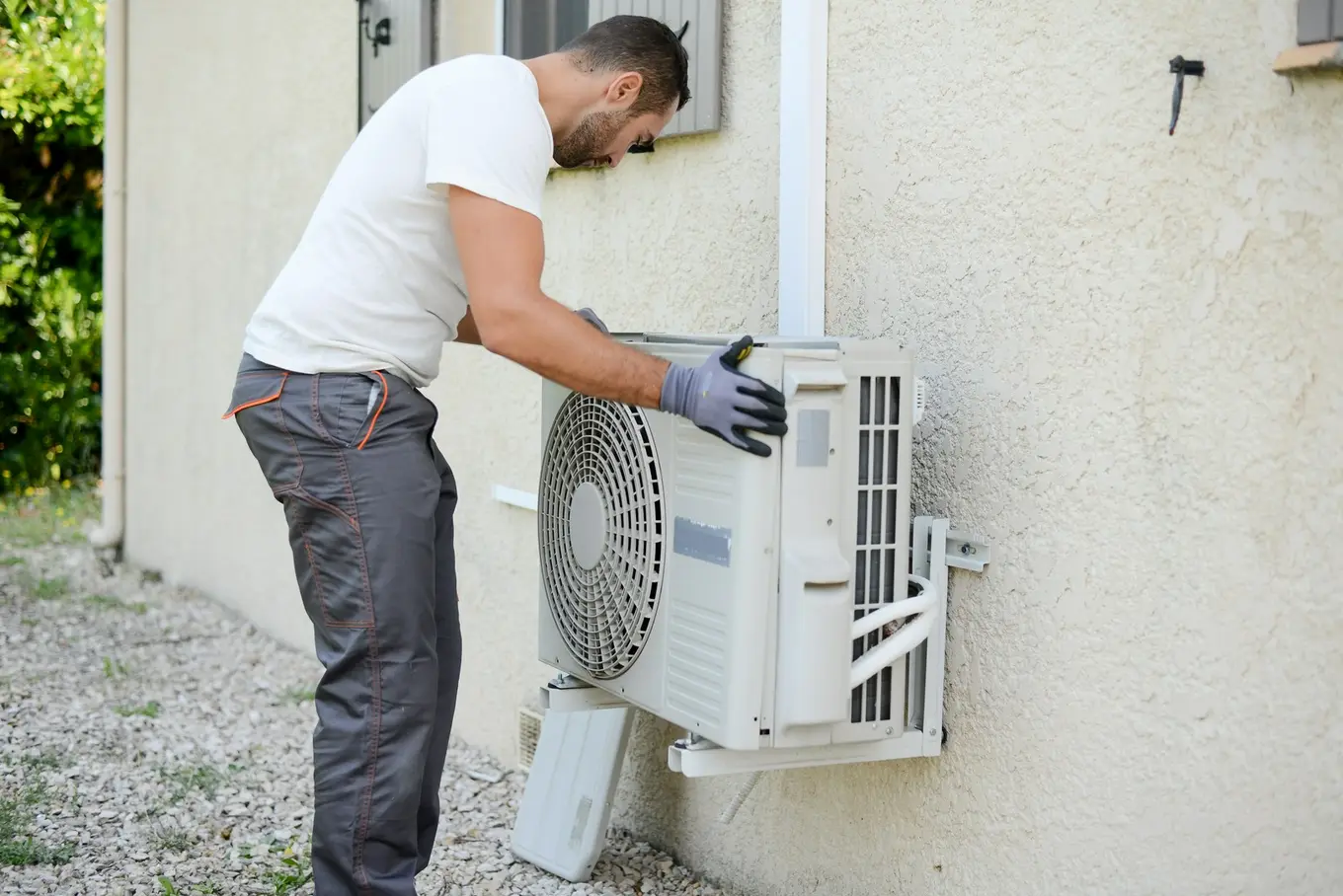 mężczyzna montuje jednostkę zewnętrzną klimatyzacji